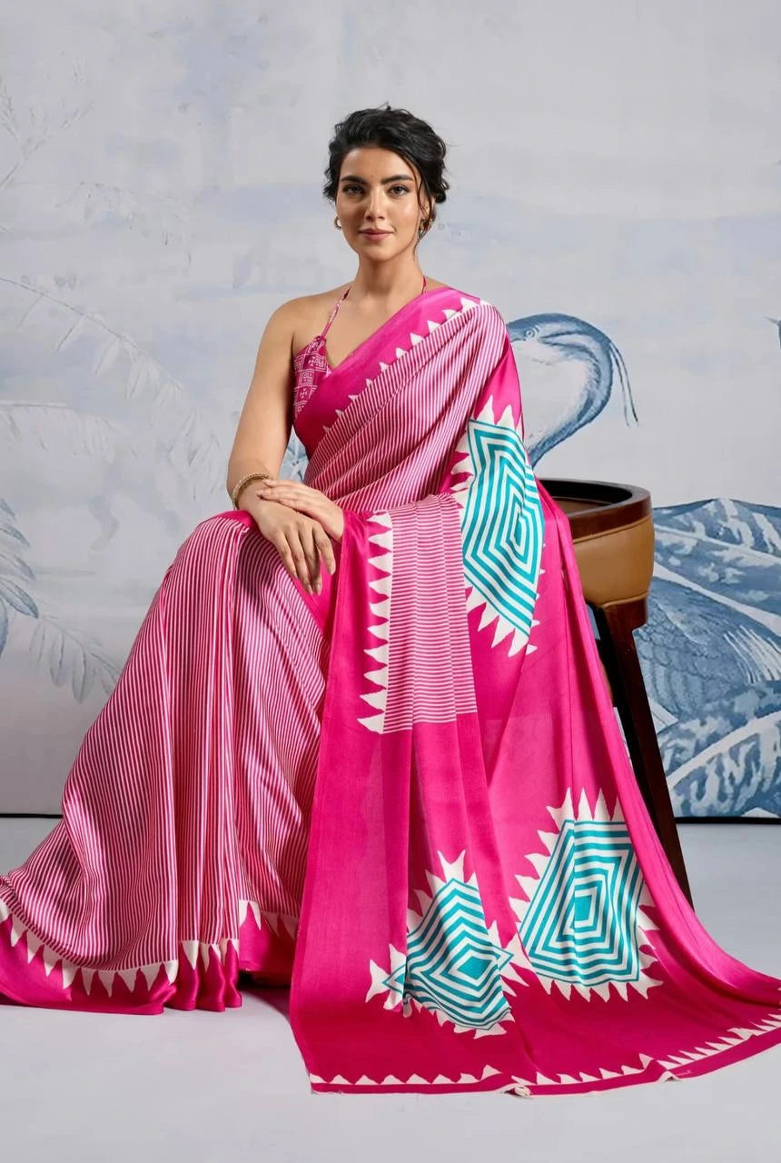 Woman wearing a pink saree with blue and white patterns against a light gray background